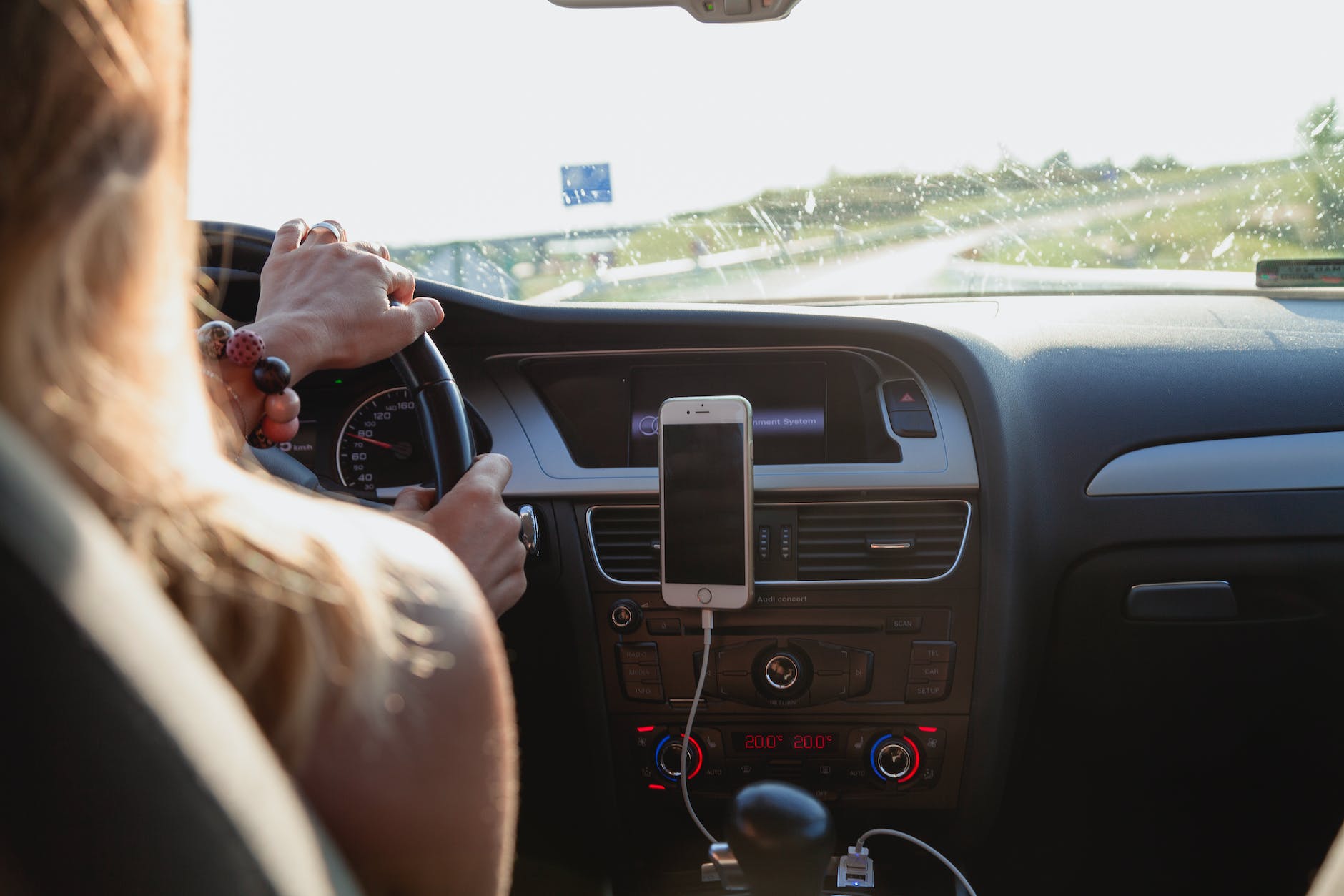 The view from the backseat, over the left shoulder of a woman driving a car.