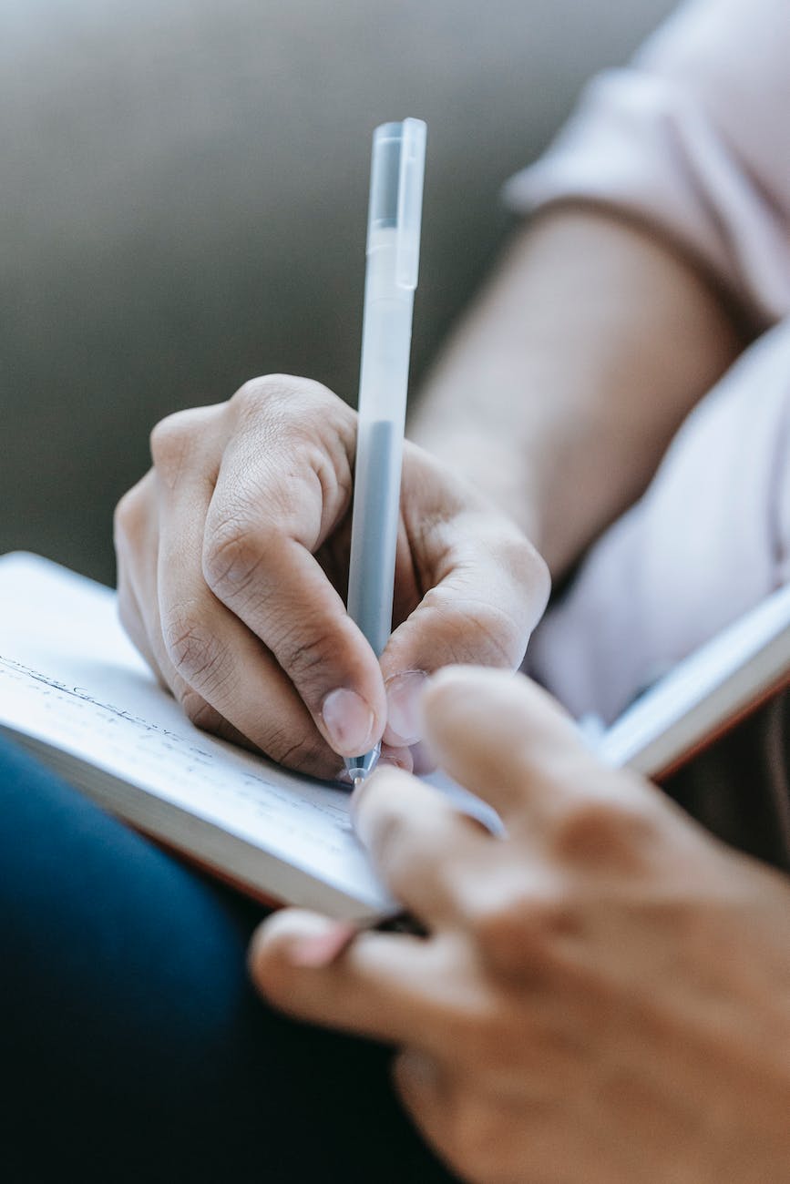 A close-up of a hand holding a pen and writing in a note book.