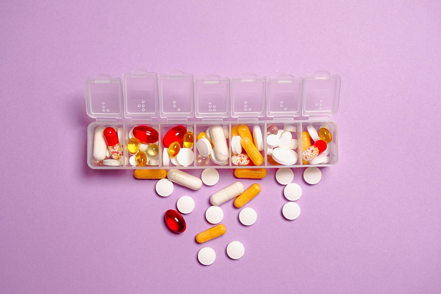 A weekly pill box filled with a variety of tablets and capsules.
