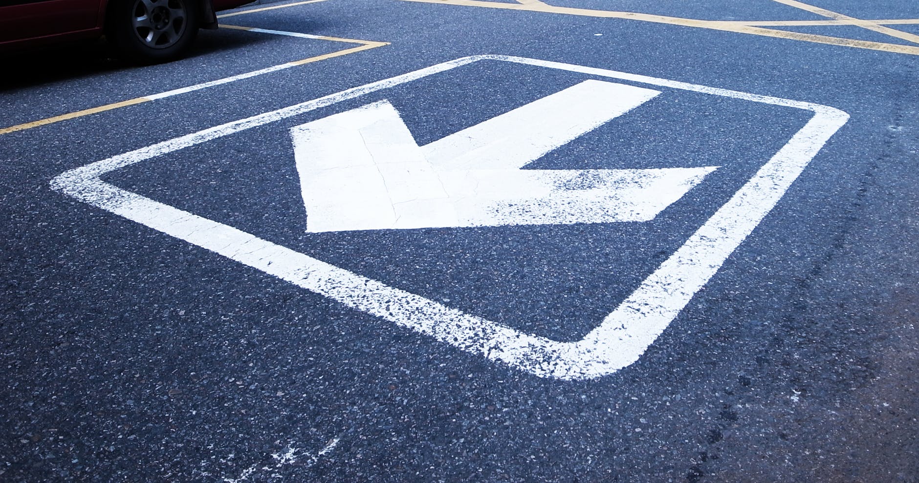 A white arrow painted on the road pointing back towards the viewer.