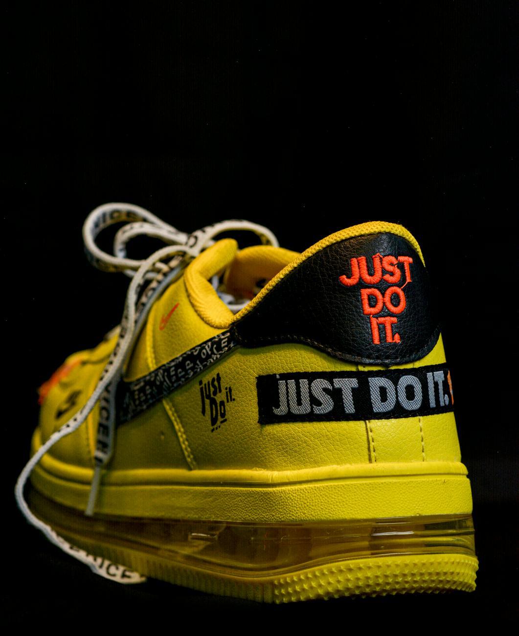 The back of a yellow running shoe says, "Just do it" in red letters and again in silver and again in black letters.