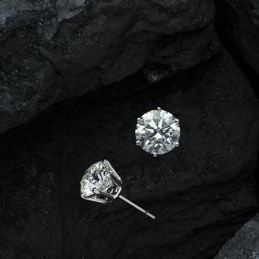 Two diamond stud earrings on a black background.