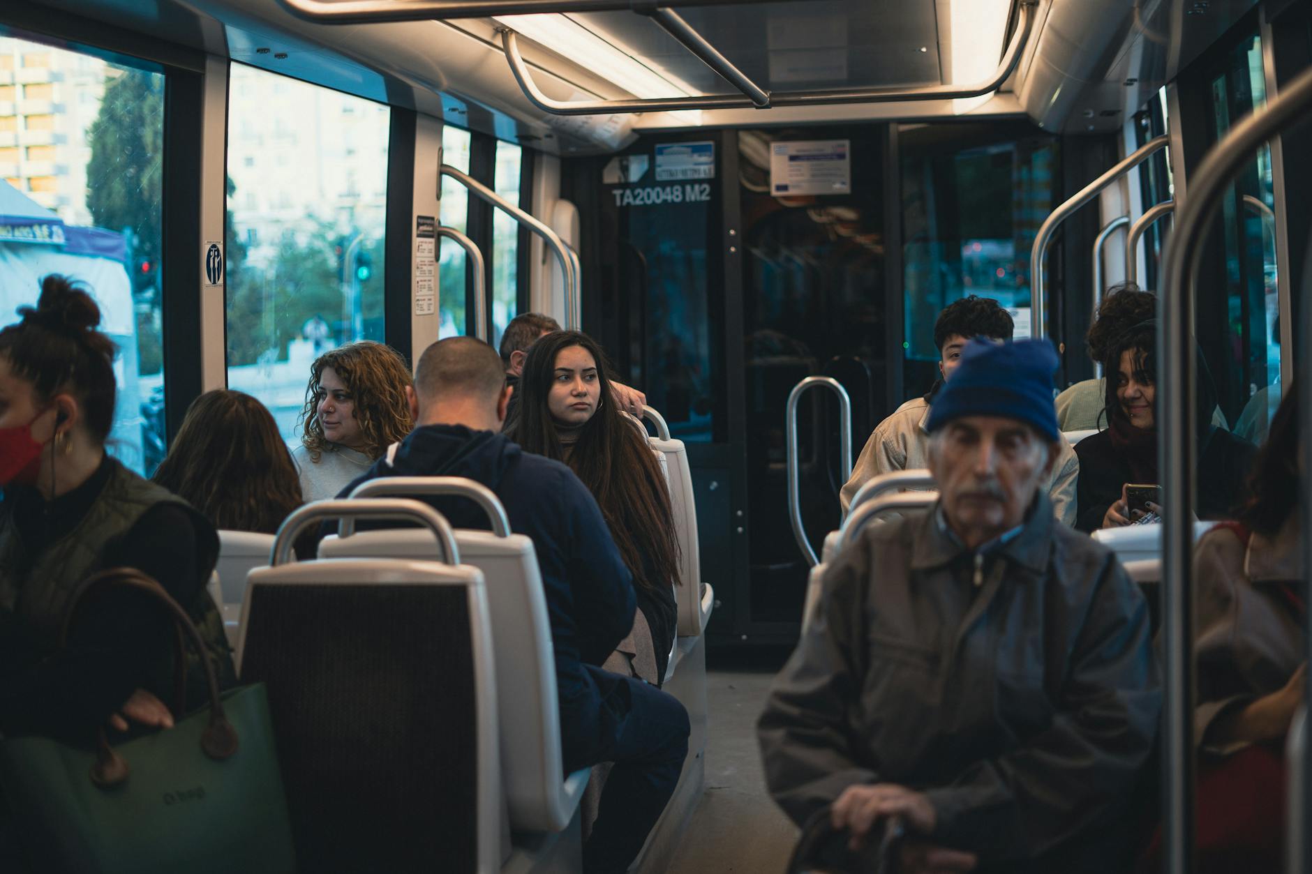 A variety of people sit quietly on a city bus.