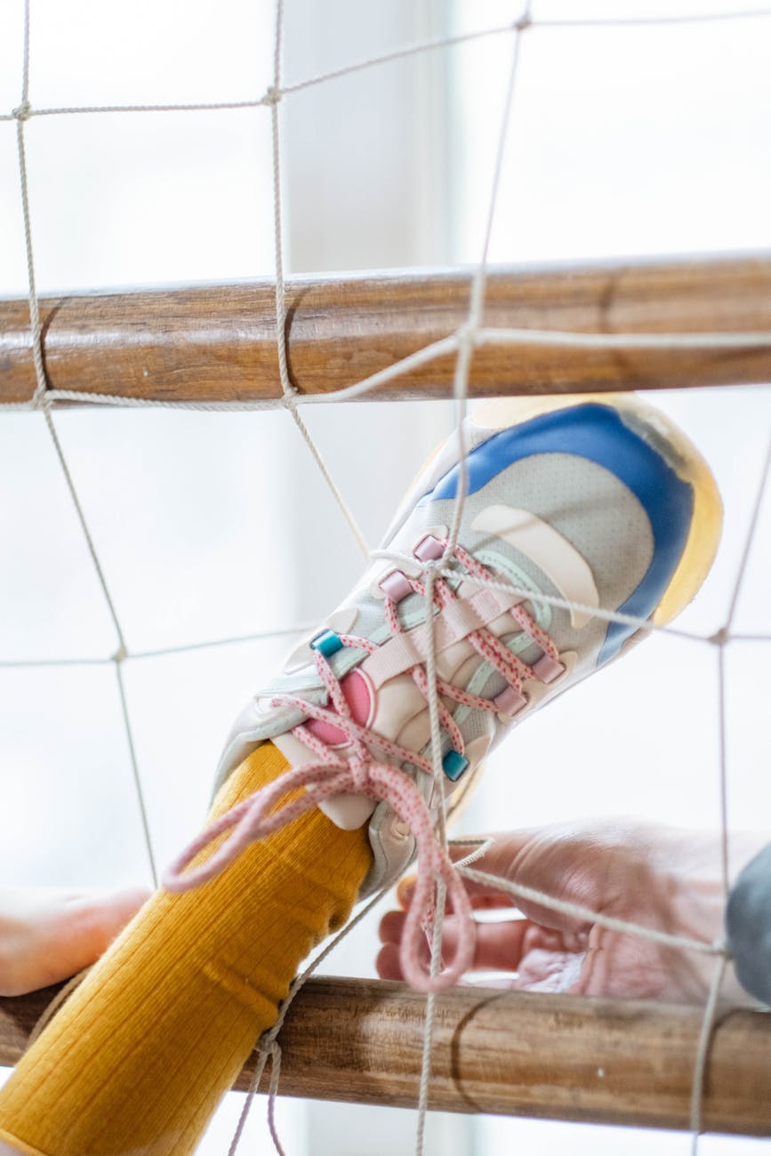 A leg with a colourful running shoe and yellow sock is stuck through a net.