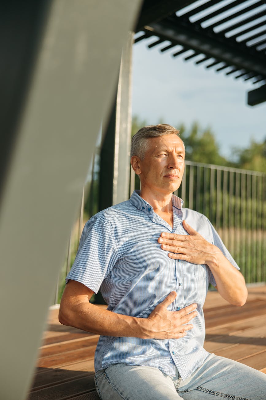 A man facing the sun with one hand on his chest and the other hand on his belly.