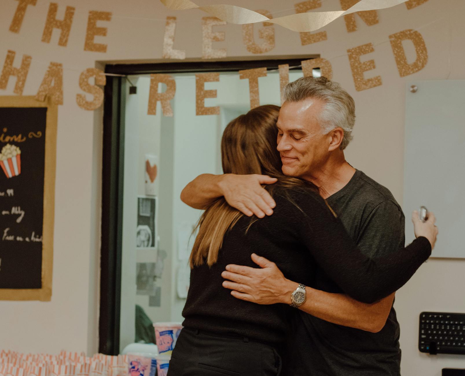 Two people embrace at a retirement party.